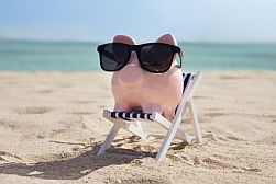 Wenn sparen Spaß macht Sparschwein mit Sonnenbrille auf Liegestuhl