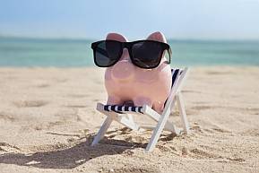 Finanziell entspannen mit einer kostenfreien Kreditkarte Sparschwein mit Sonnenbrille am Strand